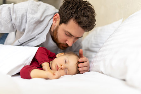 Handsome brunette father kissing sleeping infant baby tenderly.の写真素材