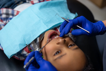 Dark-skinned boy looking scared of medical toolsの写真素材