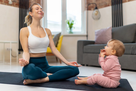 Young sporty mother and baby girl working out exercising together at home.の写真素材