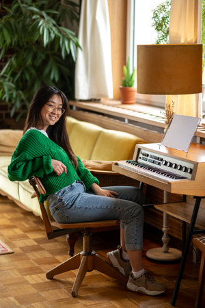 Smiling asian girl sitting near the piano at home