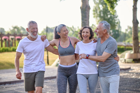 Active mature people standing together in park hugging smiling.の写真素材