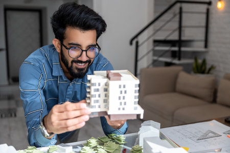Young engineer looking busy and involved while preparing a house mock upの写真素材
