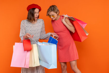 Adult women friends looking inside shopping bagsの写真素材