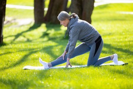 Woman in grey sportswear doing yoga in the parkの写真素材