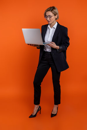 Confident woman entrepreneur wearing black official style suit working on notebookの写真素材