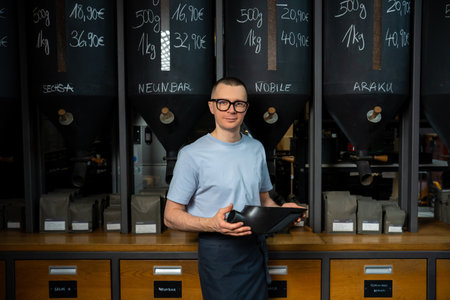 Coffee shop worker standing at counter near coffee beans.