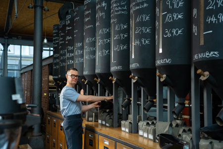 Barista roasting shop worker standing at counter pouring coffee beans.の写真素材