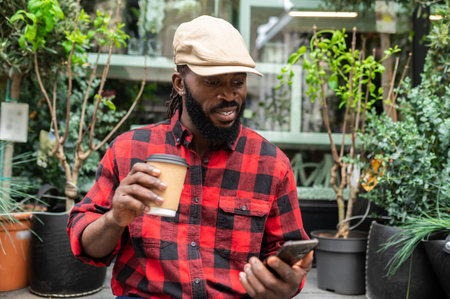 Dark-skinned man in a red plaid shirt with a coffee cup in handsの写真素材