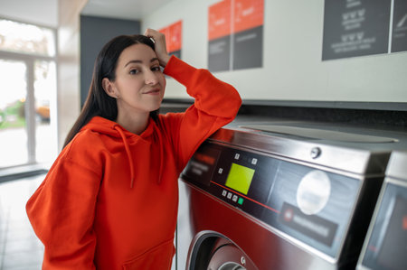 Portrait of young woman standing in the self-service public laundry.の写真素材