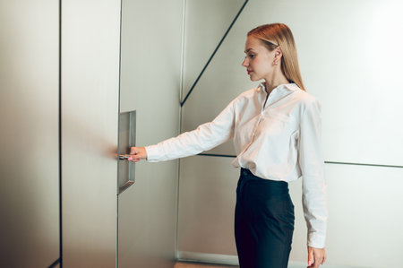 Blond young woman near the elevator in the business centerの写真素材