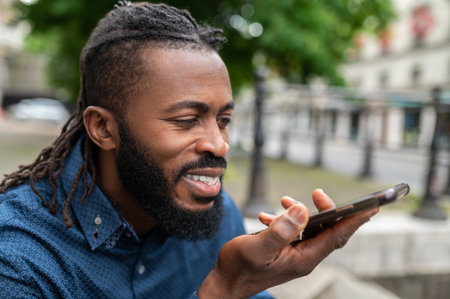 Dark-skinned young man in denim clothes with a phone in handの写真素材