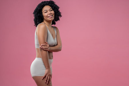 Curly-haired young woman in lingerie on pink backgroundの写真素材