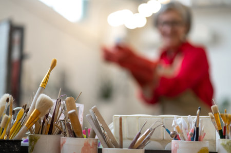 Woman enjoying creative process of pottery coloring in pottery workshop.の写真素材