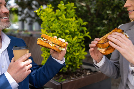 Ð¡olleagues wearing suits having lunch break, drinking coffee and eating.の写真素材