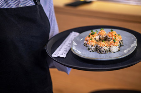 Female waitress carrying a plate with sushiの写真素材