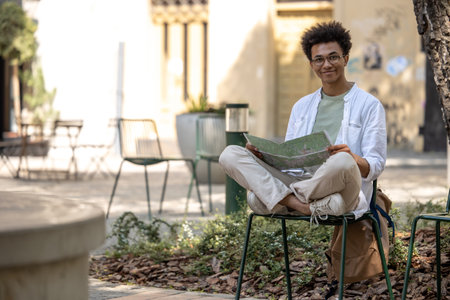 Young curly-haired tourist with a map in hands