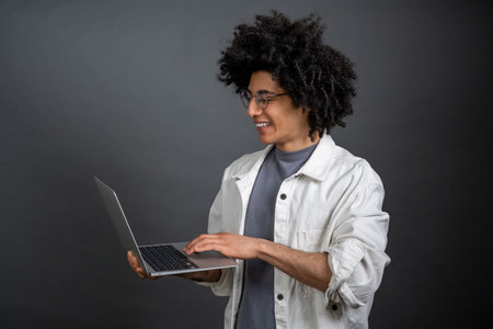 Young freelance with a laptop on grey backgroundの写真素材