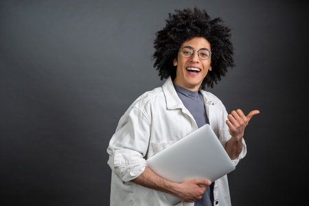 Young freelance with a laptop on grey backgroundの写真素材