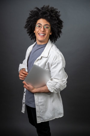 Young curly-haired digital nomad with a laptop in handsの写真素材