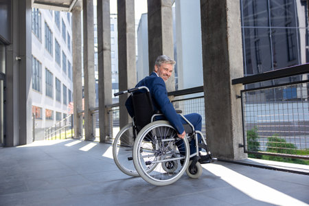 Gray haired disabled man wearing official style suit in wheelchair city background.の写真素材