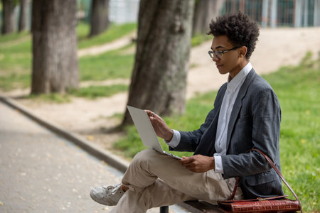 Curly-haired young digital nomad working in the parkの写真素材