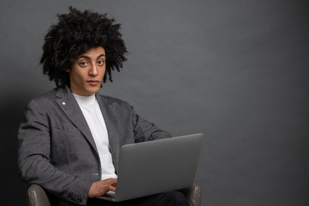 Curly-haired young manager working on laptopの写真素材