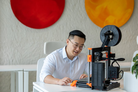 Male designer using 3D printer in office, working with new technology ideas.