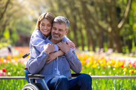 Disabled man with wife walking in park.の写真素材