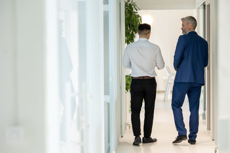 Men walking along corridor in office and talking about their work.の写真素材