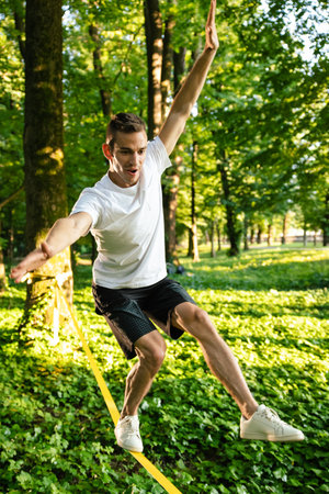 Young man in white tshirt and shorts on the rope keeping balance