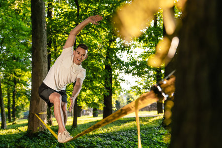 Sportsman on the rope practising slacklining and looking concentratedの写真素材