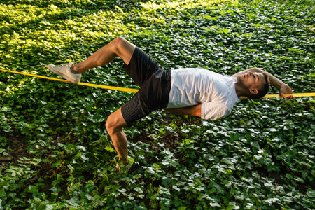 Smiling young handsome man lying on the rope and keeping balance