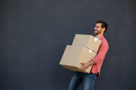 Contented young man with heavy carton boxes in hands