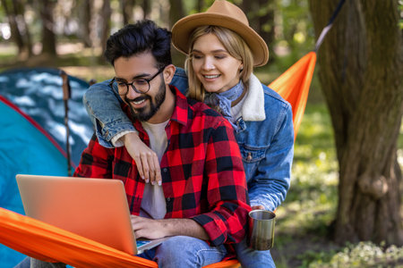 Young freelancer working on laptop in the forest, wit his girlfriend next to himの写真素材