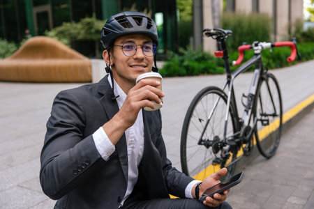 Young man in a suit and protective hempet with a coffee cup in hand