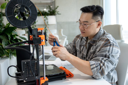 Engineering man designing mechanical parts using 3D printer in office.