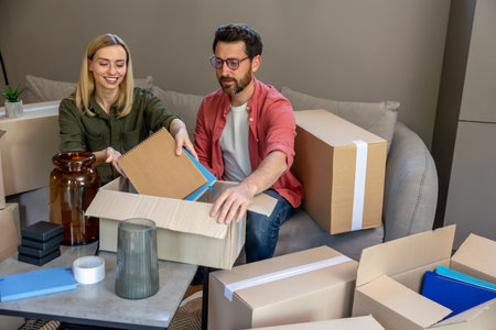 Young couple getting prepared for the relocation and packing the stuff to the boxes