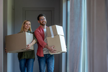 Young couple carrying cardboards with clothes while relocation