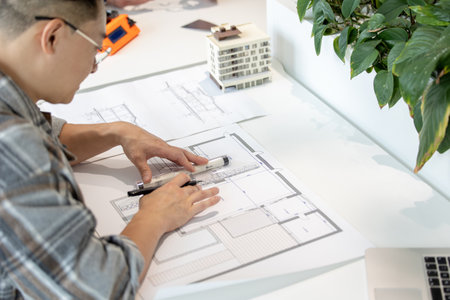 Man architect working with blueprints modeling modern house.