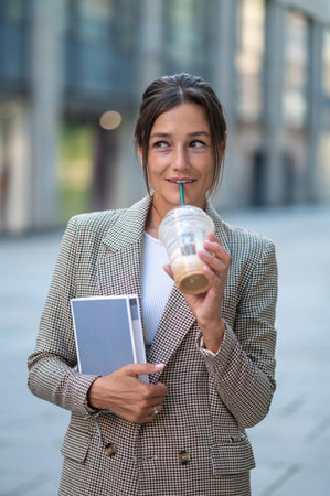 Happy woman posing outdoor drinking milk cocktail and holding organizer.の写真素材