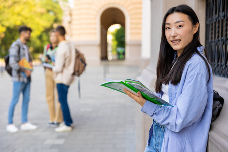 Asian long-haired girl with a notebook in the college yardの写真素材
