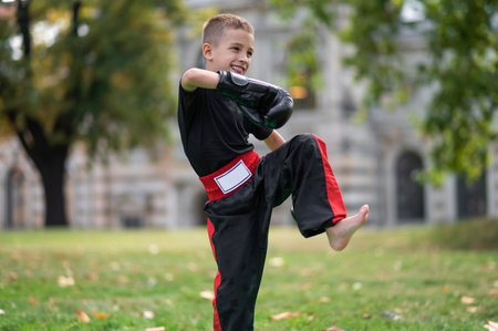 Fair-haired kid in boxing gloves exercising in the parkの写真素材