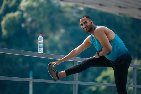 Dark-haired man in sportswear exercising and stretching his legs