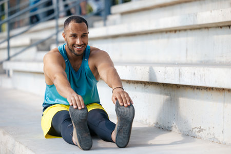 Young man in sportwear exercising and doing legs stretching