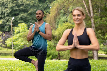 Man and woman doing yoga exercises in green park.の写真素材
