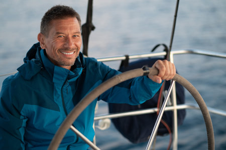 Good-looking mature man sailing a yacht and looking confident