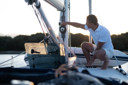 Good-looking man in white tshirt doing something on the yachtの写真素材