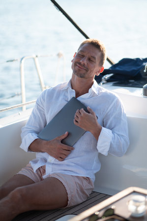 Successful mature man with a laptop working on a yacht