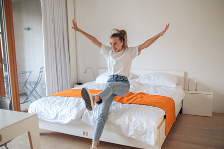 Young girl in jeans and white tshirt having fun in bedroom