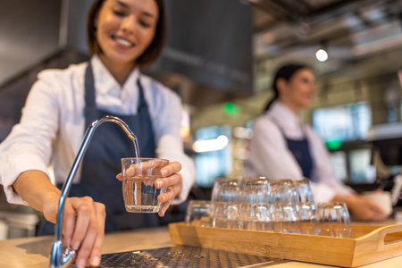 Girl in apron cleaning a cup and looking contented